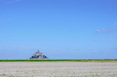 Traditional windmill on field against blue sky