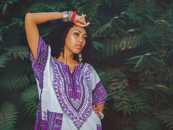 Young woman standing against plants