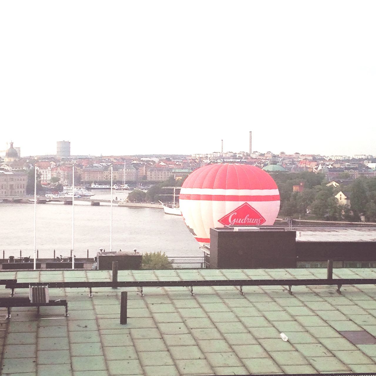 clear sky, architecture, built structure, building exterior, red, copy space, water, railing, river, day, outdoors, city, no people, transportation, sky, bridge - man made structure, connection, flag, tree, travel destinations