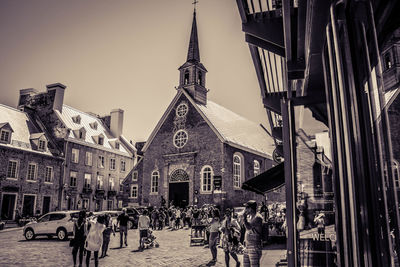 People walking in front of church against sky in city