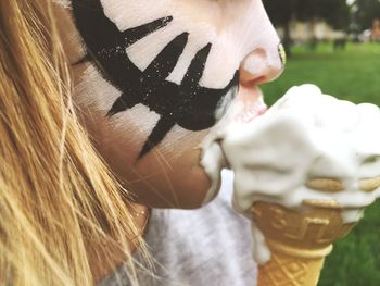 Close-up of girl with face paint eating ice cream