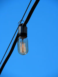 Low angle view of hanging light against clear blue sky