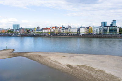 Bridge over river by buildings in city against sky