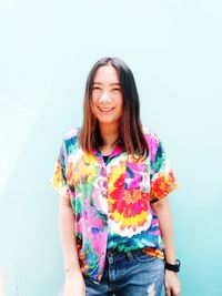 Portrait of a smiling young woman standing against white background