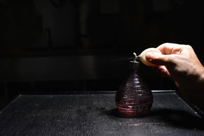 Close-up of hand holding bottle on table