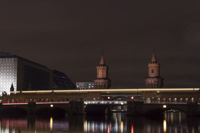 Illuminated bridge over river against sky in city at night