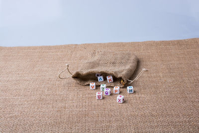 Close-up of toy blocks in sack on burlap against gray background