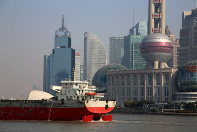 Barge on river with communication tower and buildings in background