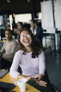 Cheerful businesswoman laughing by desk at startup company