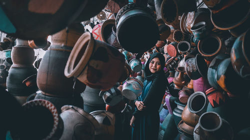 Portrait of woman wearing hijab standing amidst potteries at market