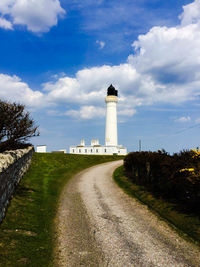 Lighthouse on landscape against sky