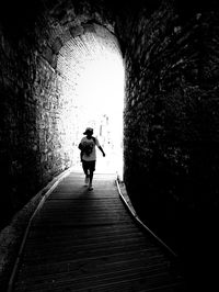 Rear view of woman walking in tunnel