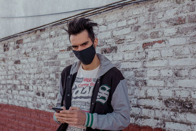 Portrait of young man with face mask in city against clear sky