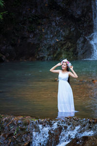 Young woman in dress standing amidst lake at forest