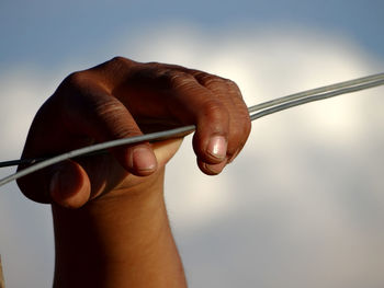 Close-up of hand holding leaf against sky