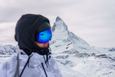 Portrait of young woman standing on snow covered mountain