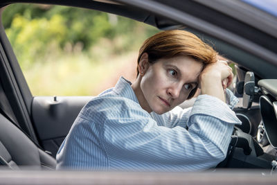 Portrait of young woman sitting in car