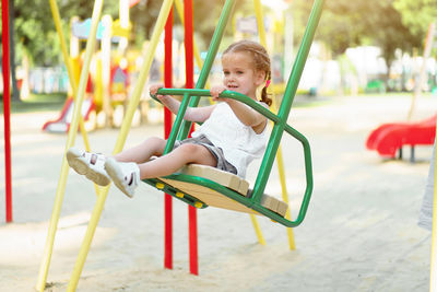 Girl sitting on swing at playground