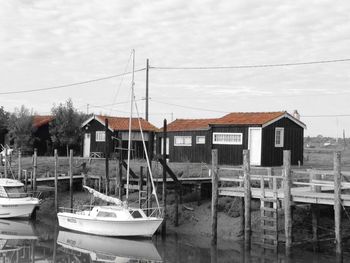 Boats moored in canal by houses against sky