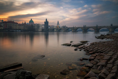 Charles bridge over river against cloudy sky