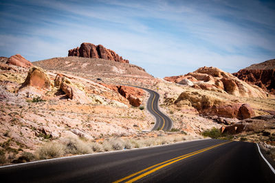 Empty road leading towards mountains against sky