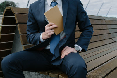 Midsection of businessman putting book in blazer