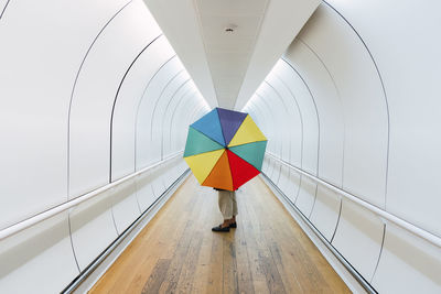 Young woman with multi colored umbrella standing on walkway