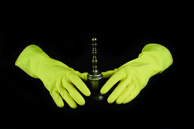 Close-up of hand holding leaf over black background