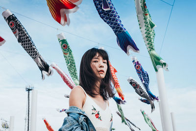 Low angle portrait of young woman standing against koinoboris