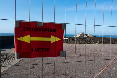 Information sign on fence against blue sky