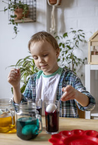 Cute boy putting egg in jar