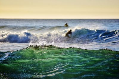 Person surfing in sea against sky