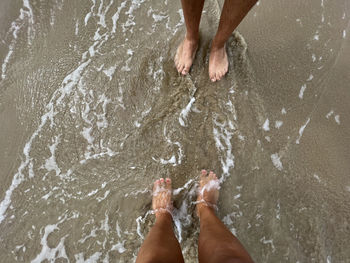 Low section of man and woman standing in water