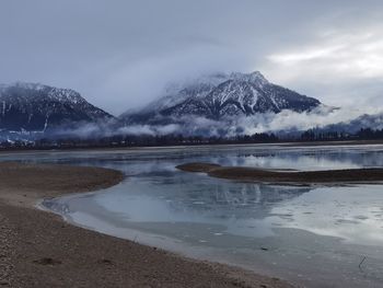 Scenic view of lake by snowcapped mountains against sky