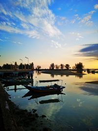 Boat moored in lake against sky during sunset