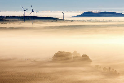 Morning fog over a rural landscape with wind turbines