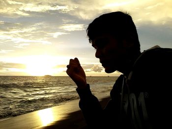 Thoughtful man standing on sea shore during sunset