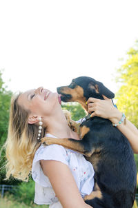 Midsection of woman with dog against sky