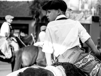 Rear view of thoughtful boy riding horse outdoors