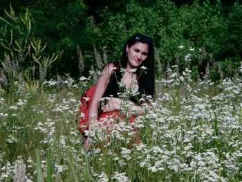 Portrait of young woman smiling amidst plants on field