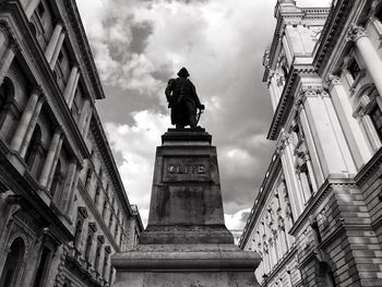 Low angle view of statue against historic building against sky