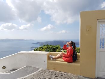 Woman sitting on seat against sky