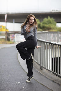 Portrait of smiling young woman standing against railing