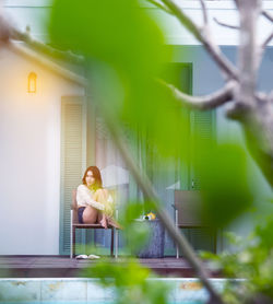 Full length of woman sitting on potted plant