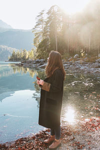 Rear view of woman standing by lake