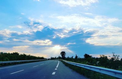 Road by trees against sky