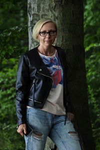 Portrait of woman standing by tree trunk