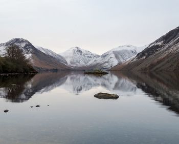 Scenic view of lake by snowcapped mountains against sky