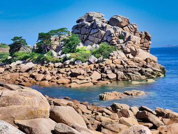 Rocks by sea against blue sky