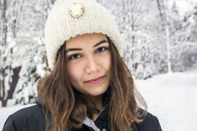 Portrait of smiling teenage girl standing against snow covered land during winter